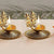 Two ornate brass diya lamps with lit candles on a light background