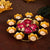 Decorative candle holder with lit candles and flowers on a dark surface