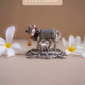 Decorative metal cow figurine with flowers on a beige background