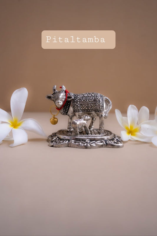 Decorative metal cow figurine with flowers on a beige background