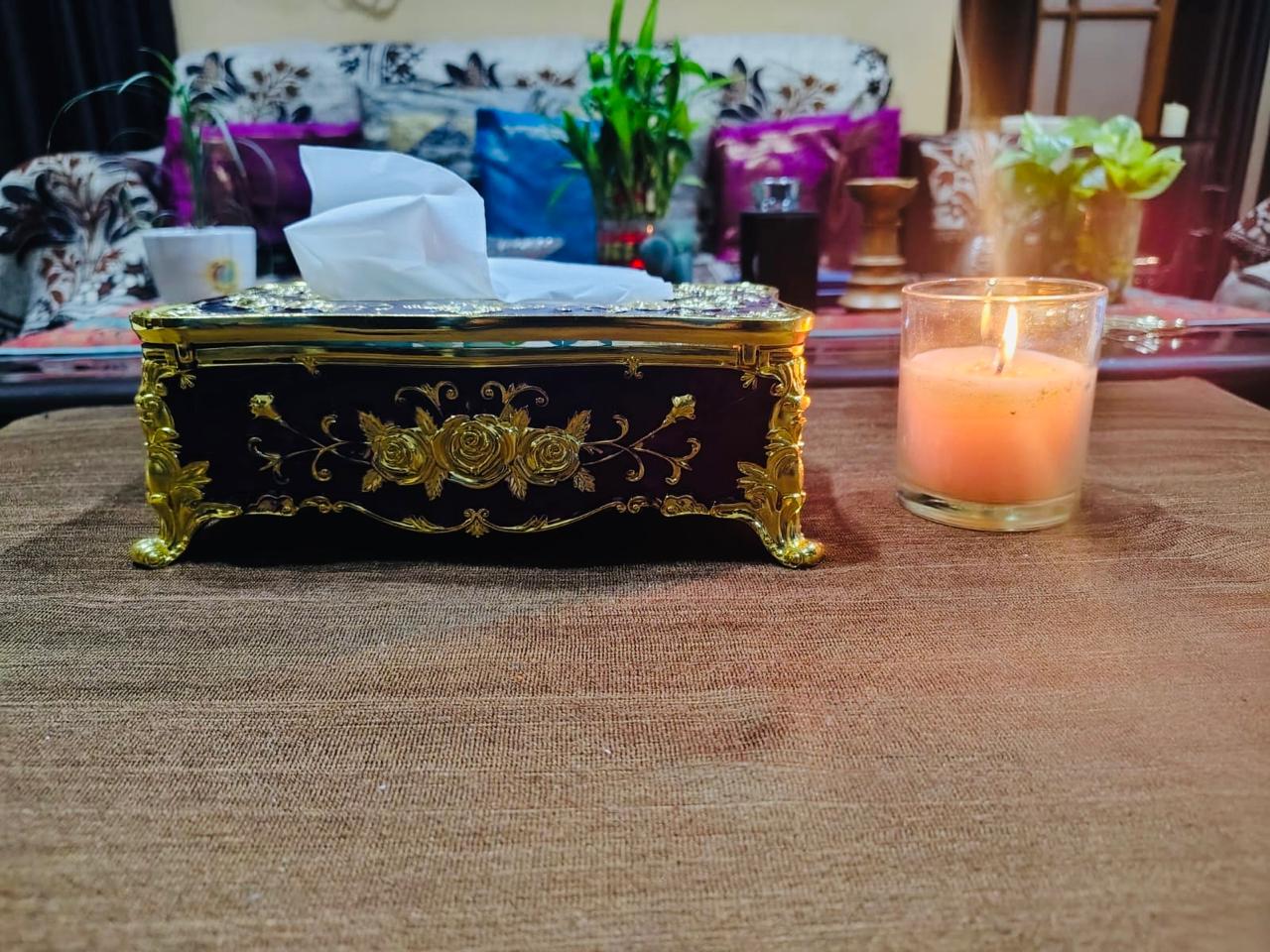 Decorative tissue box with a lit candle on a table