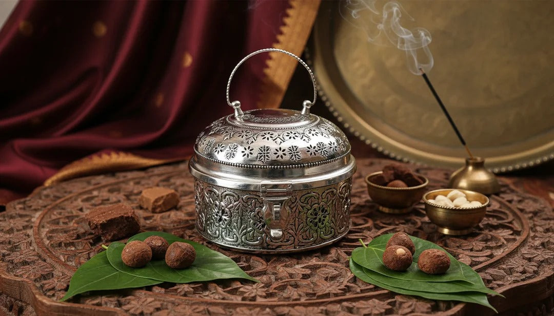 Decorative silver incense burner with burning incense stick on a textured surface.