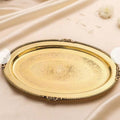 Decorative gold tray with intricate patterns on a beige fabric background