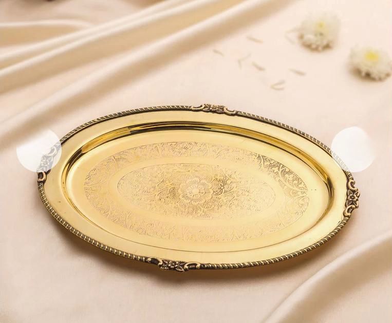 Decorative gold tray with intricate patterns on a beige fabric background