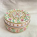 Decorative round box with floral patterns on a white fabric background