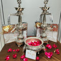 Decorative silver lamps with rose petals and a card on a brown surface.