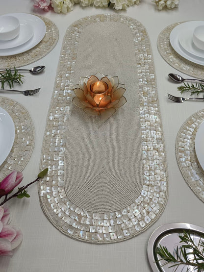 Decorative table setting with a mosaic runner, candles, and floral arrangements.