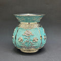 Decorative turquoise vase with floral patterns on a gray background