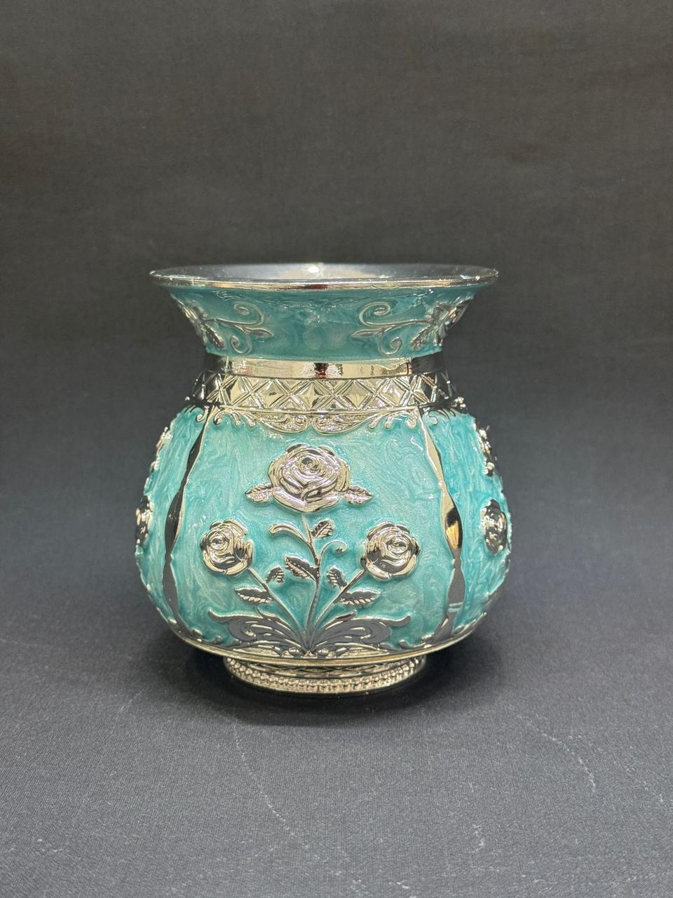 Decorative turquoise vase with floral patterns on a gray background