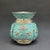 Decorative turquoise vase with floral patterns on a gray background