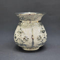 Decorative silver vase with floral patterns on a gray background
