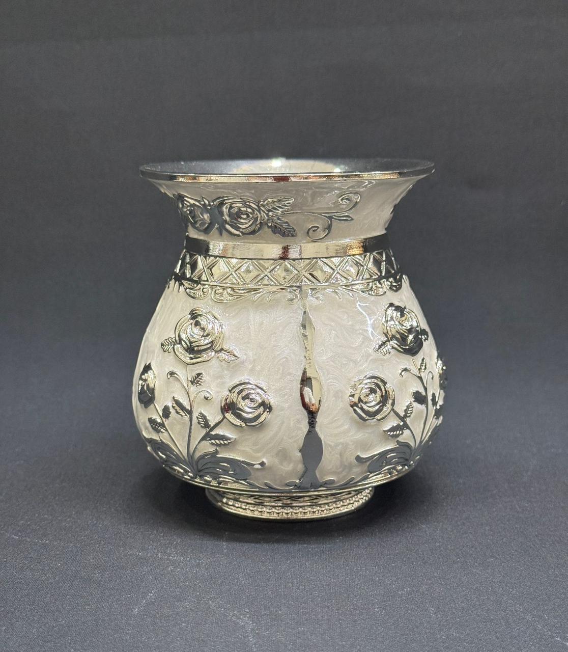 Decorative silver vase with floral patterns on a gray background