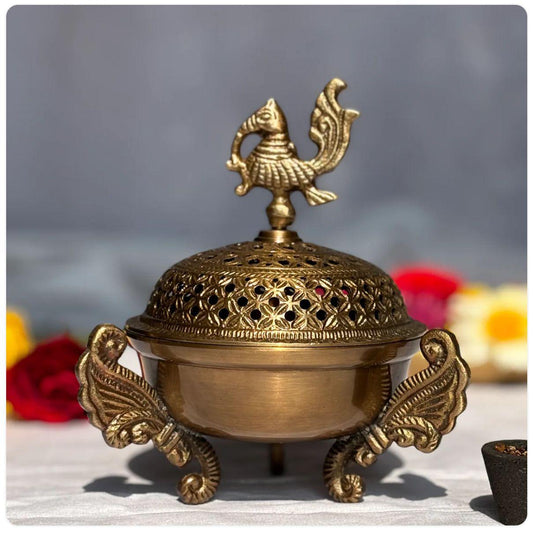 Bronze incense burner with decorative top on a gray background