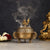Bronze incense burner with smoke, flowers, and a statue on a dark background