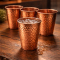 Three copper cups on a wooden surface with a blurred background