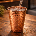 Copper cup being filled with water on a wooden surface