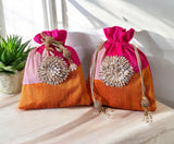 Two decorative bags with pink top and orange bottom on a light surface.