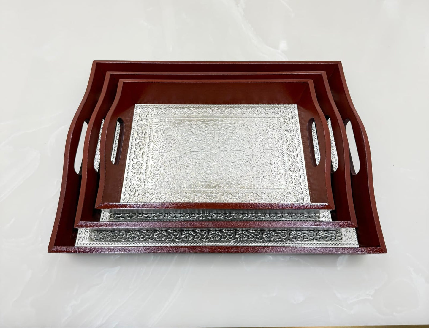 Two decorative trays with wooden frames on a white marble surface