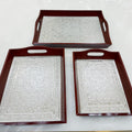 Three decorative trays with embossed patterns on a white surface