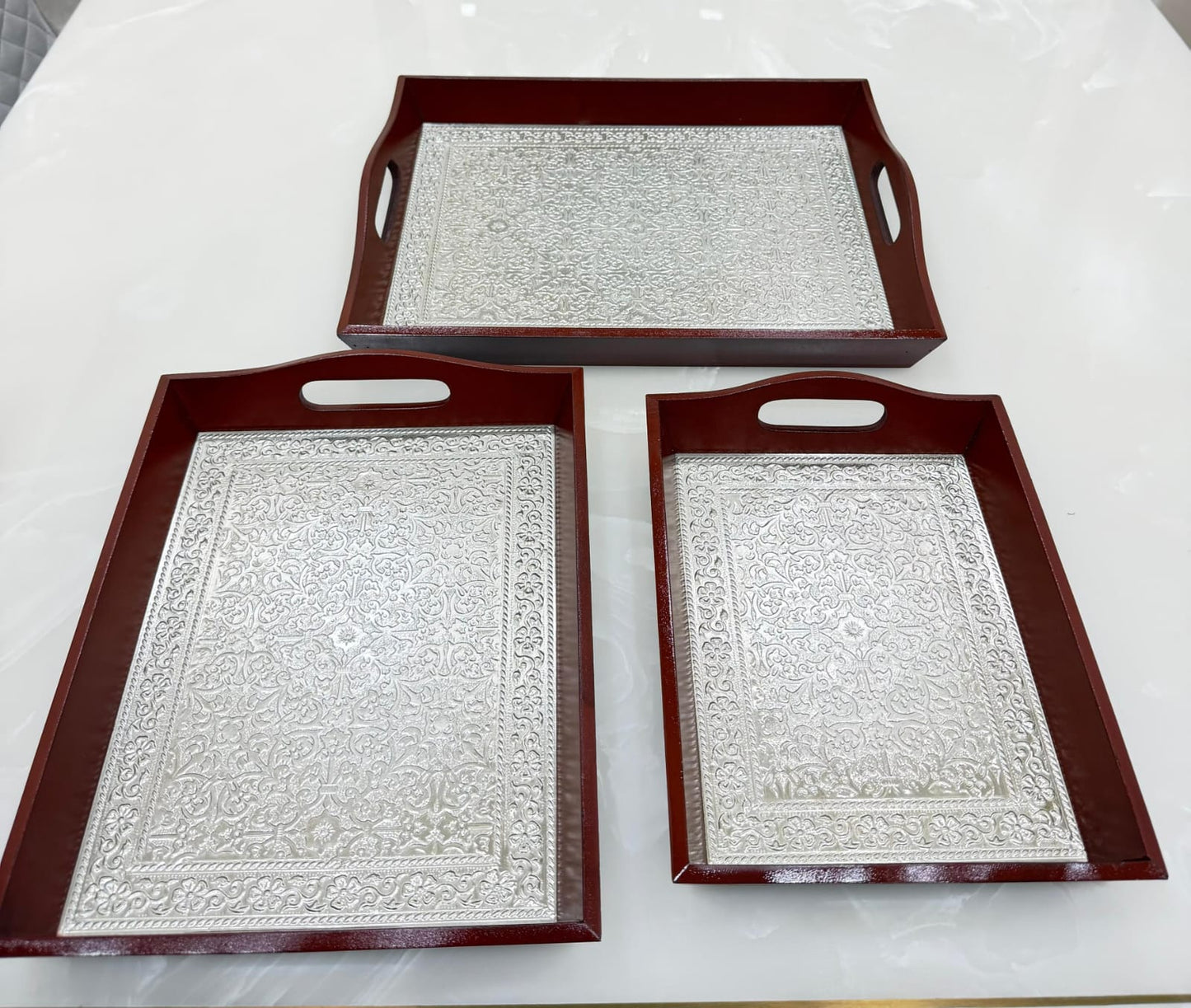 Three decorative trays with embossed patterns on a white surface