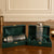 Two glass bottles with silver caps in green velvet boxes on a wooden surface.