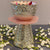 Decorative silver bowl on a pink stand with white flowers on a gray surface