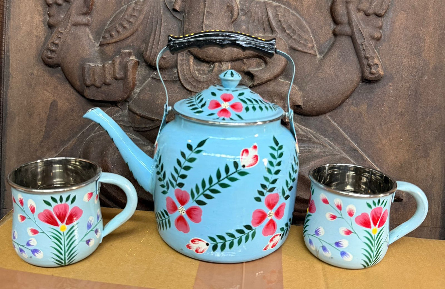 Blue floral teapot with two matching cups on a wooden surface