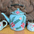 Blue floral teapot with two matching cups on a wooden surface
