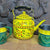 Decorative yellow teapot with floral patterns and matching cups on a wooden surface.