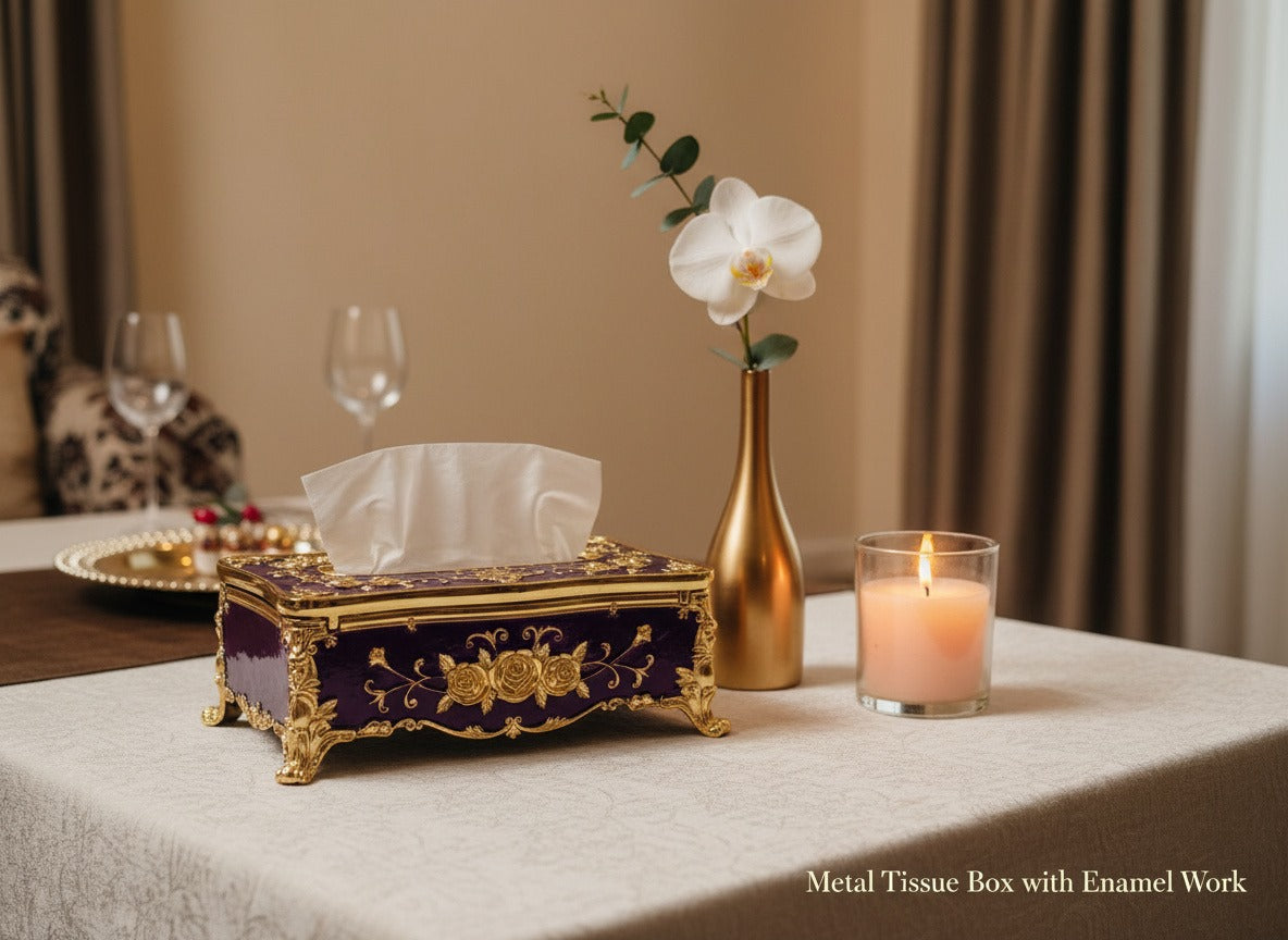 Decorative metal tissue box with enamel work on a table with a candle and vase.