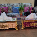 Two ornate tissue boxes on a table with a blurred background