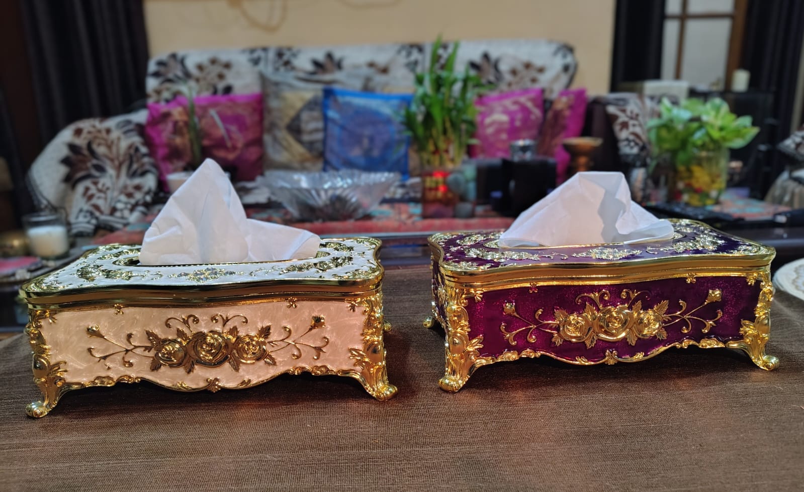 Two ornate tissue boxes on a table with a blurred background