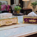Two decorative tissue boxes on a marble surface with a blurred indoor background.