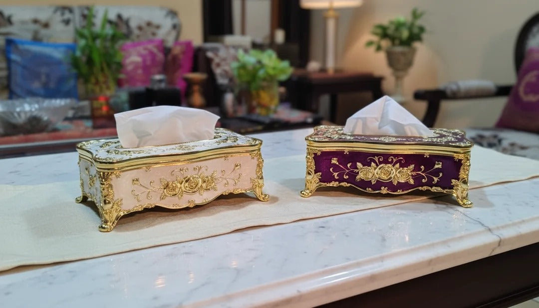 Two decorative tissue boxes on a marble surface with a blurred indoor background.