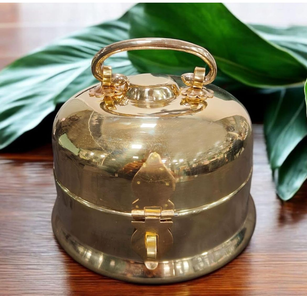 Gold bell on a wooden surface with green leaves in the background