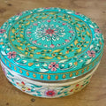 Decorative round box with floral patterns on a wooden surface