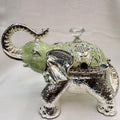 Decorative elephant figurine with a green gem on a white background