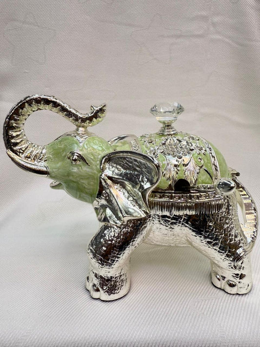 Decorative elephant figurine with a green gem on a white background