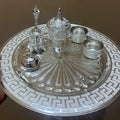 Decorative silver tray with intricate designs and small containers on a brown background