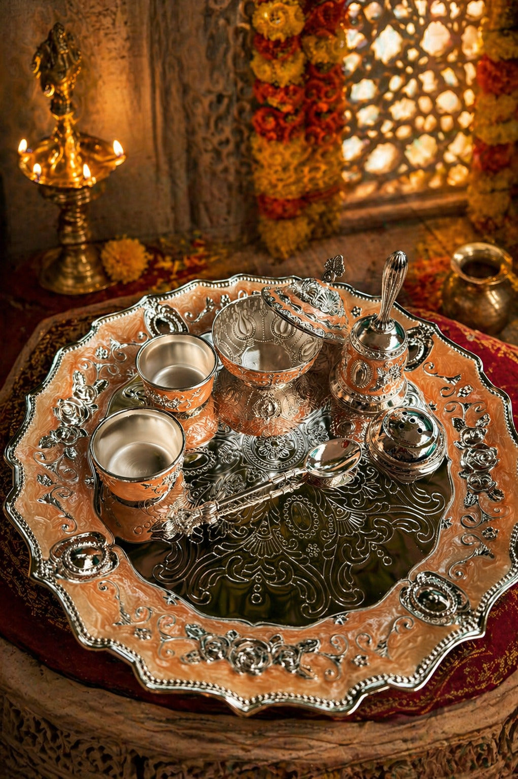 Decorative silver tray with cups and a bowl on a wooden surface.