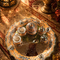 Decorative silver tray with teapot and cups on a textured surface