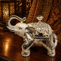 Decorative silver elephant with a glass container on a wooden surface