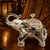 Decorative silver elephant with a glass container on a wooden surface