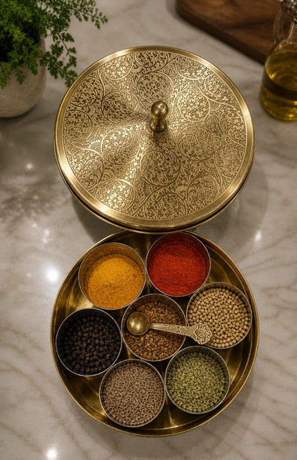 Decorative brass spice holder with various spices on a marble surface