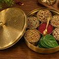 Decorative brass container with spices and leaves on a wooden surface