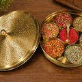 Decorative brass box with colorful spices on a wooden surface