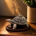Decorative turtle sculpture on a wooden surface with a plant in the background