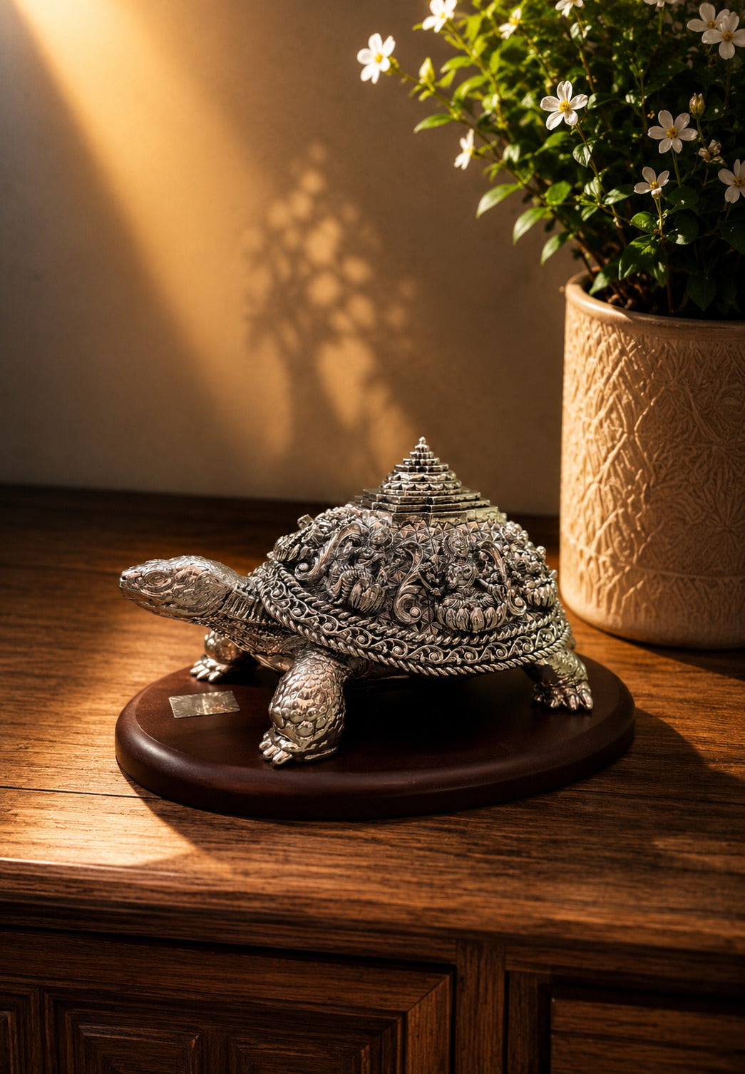 Decorative turtle sculpture on a wooden surface with a plant in the background