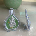 Green and silver religious icon in a clear holder on a light surface