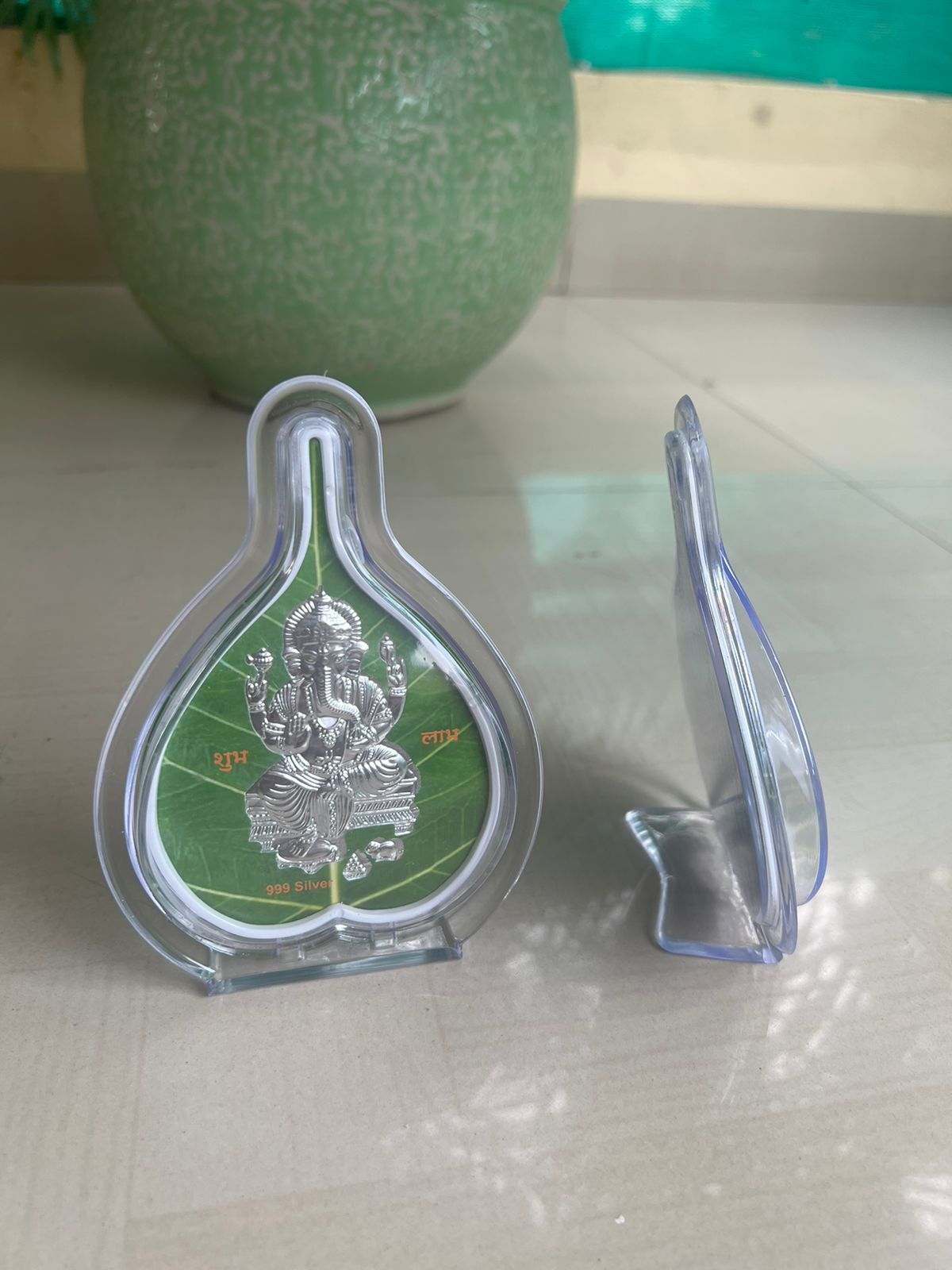 Green and silver religious icon in a clear holder on a light surface